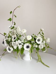 an arrangement of white and black flowers in a vase