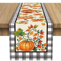 a table runner with an orange pumpkin and leaves on it