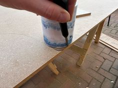 a hand is holding a black pen over a table that has been built into it