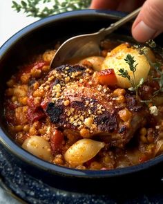 a person is spooning some food out of a bowl with meat and potatoes in it