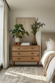 a bed room with a neatly made bed and a plant on top of the dresser