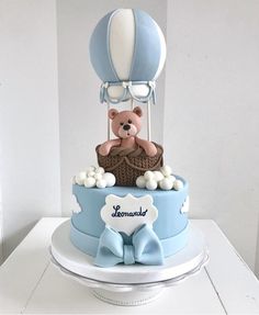 a blue and white cake with a teddy bear in a hot air balloon