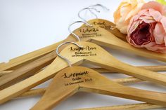 wooden clothes hangers with names on them and a flower in the middle one for each