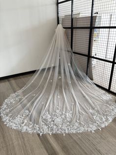 a white wedding veil on the floor in front of a caged area with wooden floors