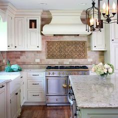 a kitchen with white cabinets and marble counter tops