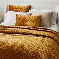 a bed that has some pillows on it and is made up with gold velvets