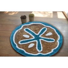 a blue and brown door mat with a sand dollar symbol on it next to two succulents