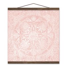 a pink and white wall hanging with an ornate design on the front, along with a wooden frame