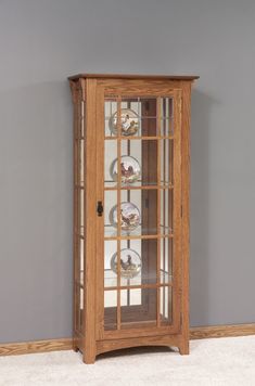 a wooden display case with glass doors on the top and bottom shelves, in front of a gray wall