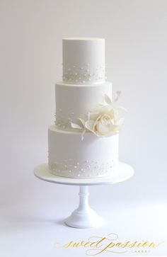 a three tiered white wedding cake with flowers on top