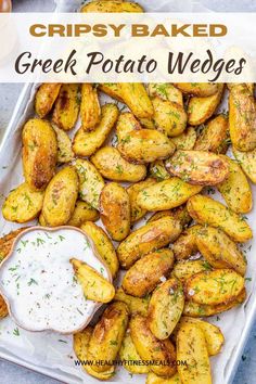 crispy baked greek potato wedges on a tray with ranch dip in the middle