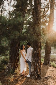 a man and woman standing next to each other in the woods