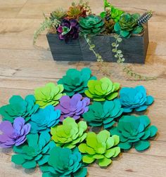 paper flowers sitting on top of a wooden table next to succulents and plants