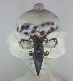 a woman's head wearing a mask with feathers and jewels on top of it