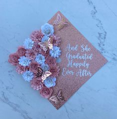 pink and blue flowers are on top of a card that says, she graduated happily after