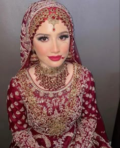 a woman wearing a red and gold wedding outfit