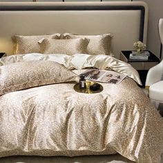 the bed is made up with gold sheets and pillows, along with two white chairs