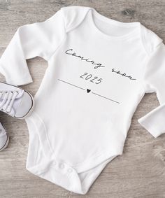 a baby's bodysuit with the words coming soon and a pair of sneakers