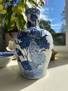 a blue and white vase sitting on top of a table next to a potted plant