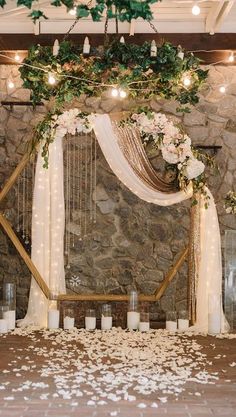 a wedding ceremony with candles and flowers on the floor in front of a stone wall