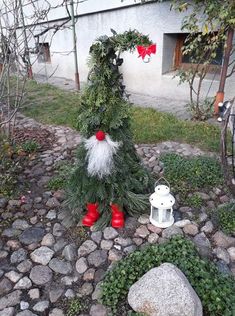 a christmas tree with red boots on it in the middle of a stone path next to a house