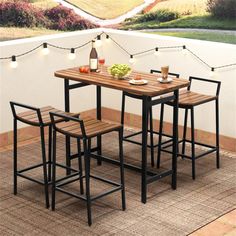 an outdoor table with four stools and lights on the wall above it, next to a rug