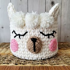 a crocheted white llama hat with pink eyes