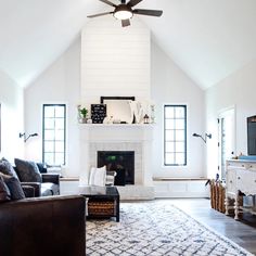 a living room with white walls and ceiling fan