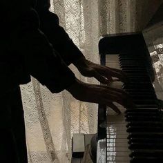 a person playing the piano in front of a window with lace curtain behind it and curtains on either side