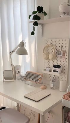 a white desk topped with a laptop computer next to a lamp and potted plant