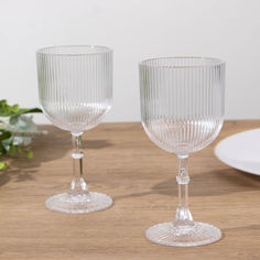 two glass goblets sitting on top of a wooden table next to each other