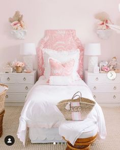 a bedroom with pink walls and white bedding, wicker baskets on the floor