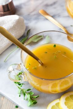 a glass bowl filled with liquid next to sliced lemons on a marble counter top