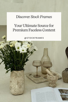 a table topped with vases filled with white flowers and plants next to an open book