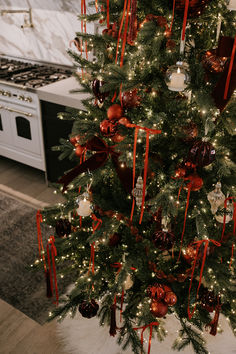 a decorated christmas tree in a kitchen with red and white ornaments on it's branches