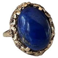 Crafted in the 1950s, this striking vintage cocktail ring is set with a natural lapis lazuli oval-shaped cabochon measuring 11.09 X 15.39mm and weighing approximately 8.59 carats. It is mounted in 14k yellow gold with delicate piercing. Luxury Oval Cabochon Sapphire Ring, Luxury Sapphire Ring In Oval Cabochon Shape, Luxury Oval Elegant Cabochons, Luxury Vintage Oval Cabochon Dome Ring, Luxury Classic Oval Cabochon Diamond Ring, Vintage Sapphire Ring With Oval Cabochon, Vintage Dome Ring With Polished Oval Cabochon, Vintage Dome Ring With Oval Cabochon Polished Finish, Vintage Oval Gemstone Dome Ring