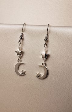 A set of earrings that feature moon and star charms along with small white pearls.  The hooks are made of nickel-free stainless steel.