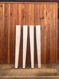 three tall white vases sitting on top of a wooden shelf in front of a wood paneled wall