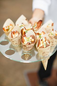 a person holding a tray with food on it and cones in the shape of cones