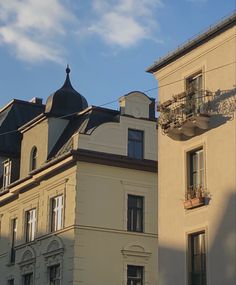 an apartment building with many windows and balconies on the top floor, against a blue sky with white clouds