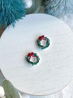 two christmas wreath earrings sitting on top of a table