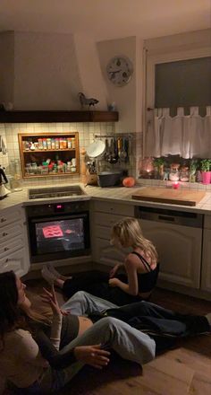 three women sitting on the floor in front of an oven