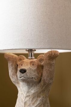 a ceramic bear lamp with a white shade on it's head and paws in the air