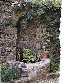 there is a stone wall with plants growing out of it and an arch in the middle