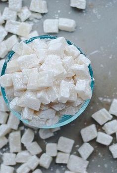 sugar cubes are in a glass bowl on a gray countertop next to a spoon