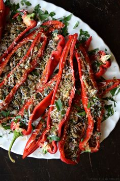 some red peppers on a white plate with parmesan cheese and seasoning sprinkles