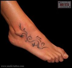 a tattoo on the foot of a woman with swirls and leaves in it,