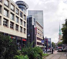 a train track running through a city with tall buildings on both sides and trees in the foreground