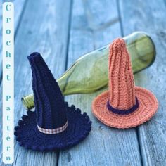 two crocheted hats sitting on top of a wooden table next to a bottle