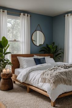 a bedroom with blue walls, white bedding and a wooden headboard in front of a window